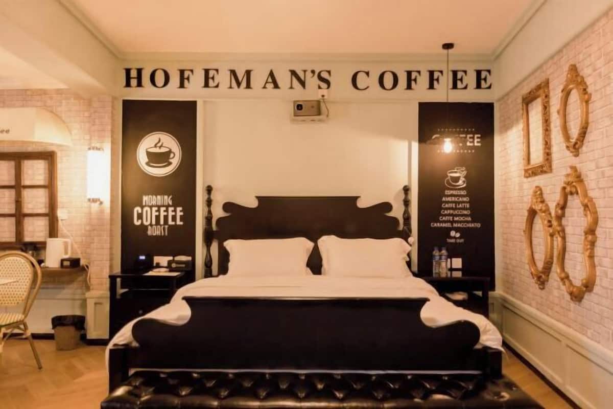 Ett hotellrum med en säng, ett nattduksbord och en kaffeskylt som hänger på väggen.