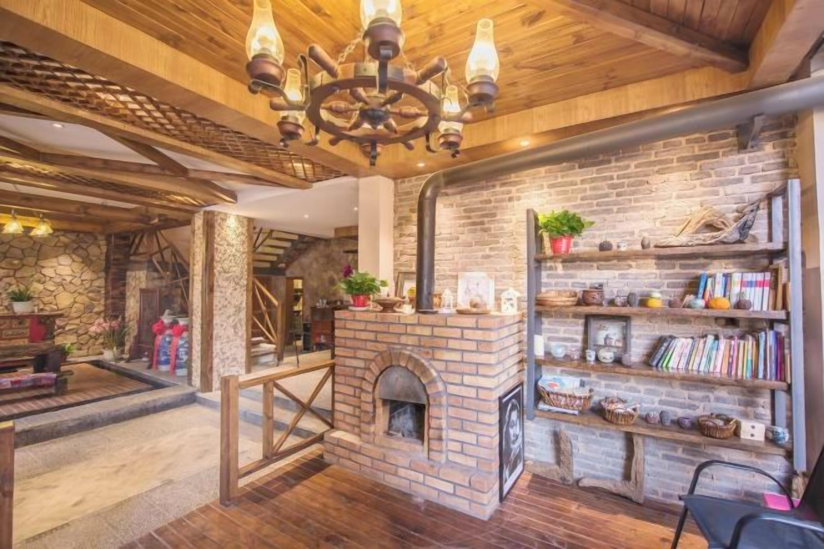 Un interior rústico con paredes de ladrillo visto, chimenea, vigas de madera y una estantería.