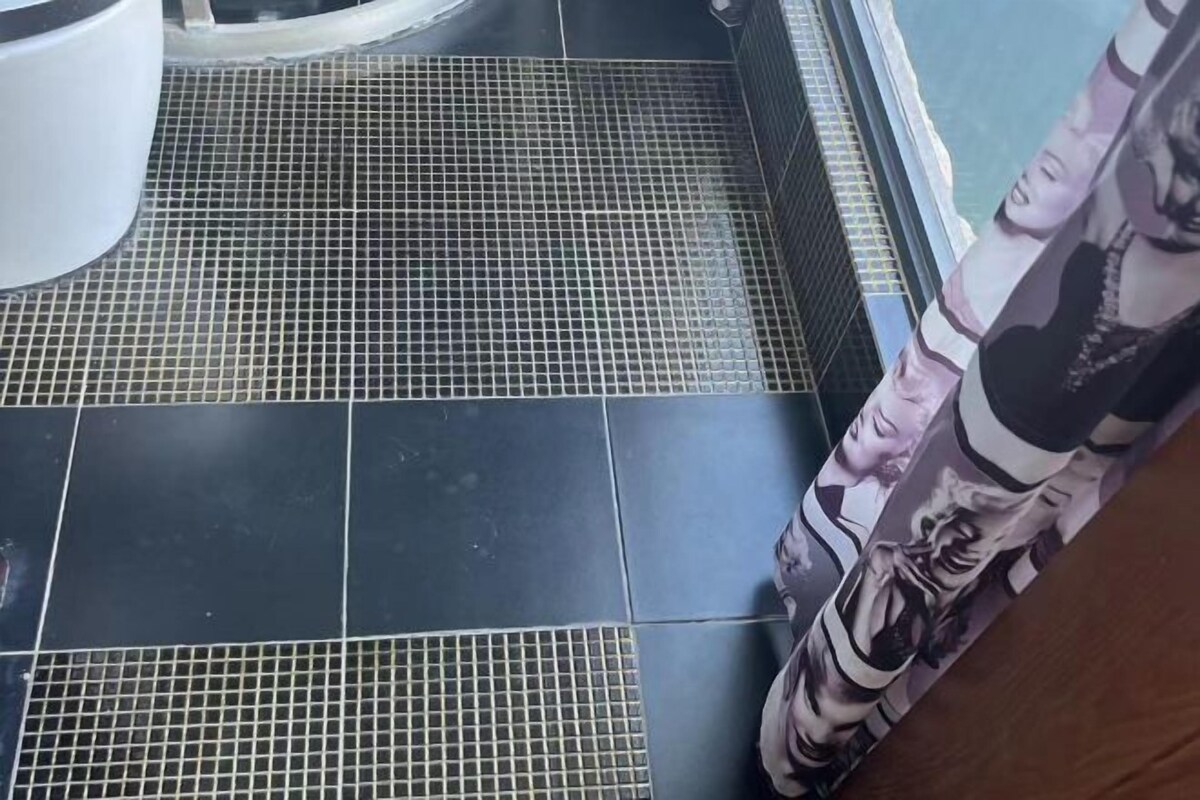 A tiled floor with a grid pattern, a white object on the left, and a curtain with a portrait design.