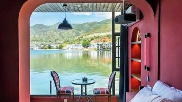 Una habitación con cama, una mesa con sillas y vistas a un lago y un paisaje montañoso.