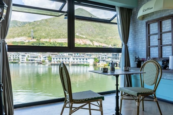 A room with a table and two chairs, a window with a view of boats and hills, and a sign reading 'Coffee'. - Dali Old Time Seaview Inn (Dali City)