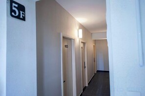 Un pasillo con puertas, cada una con un número, que dan a varias habitaciones.