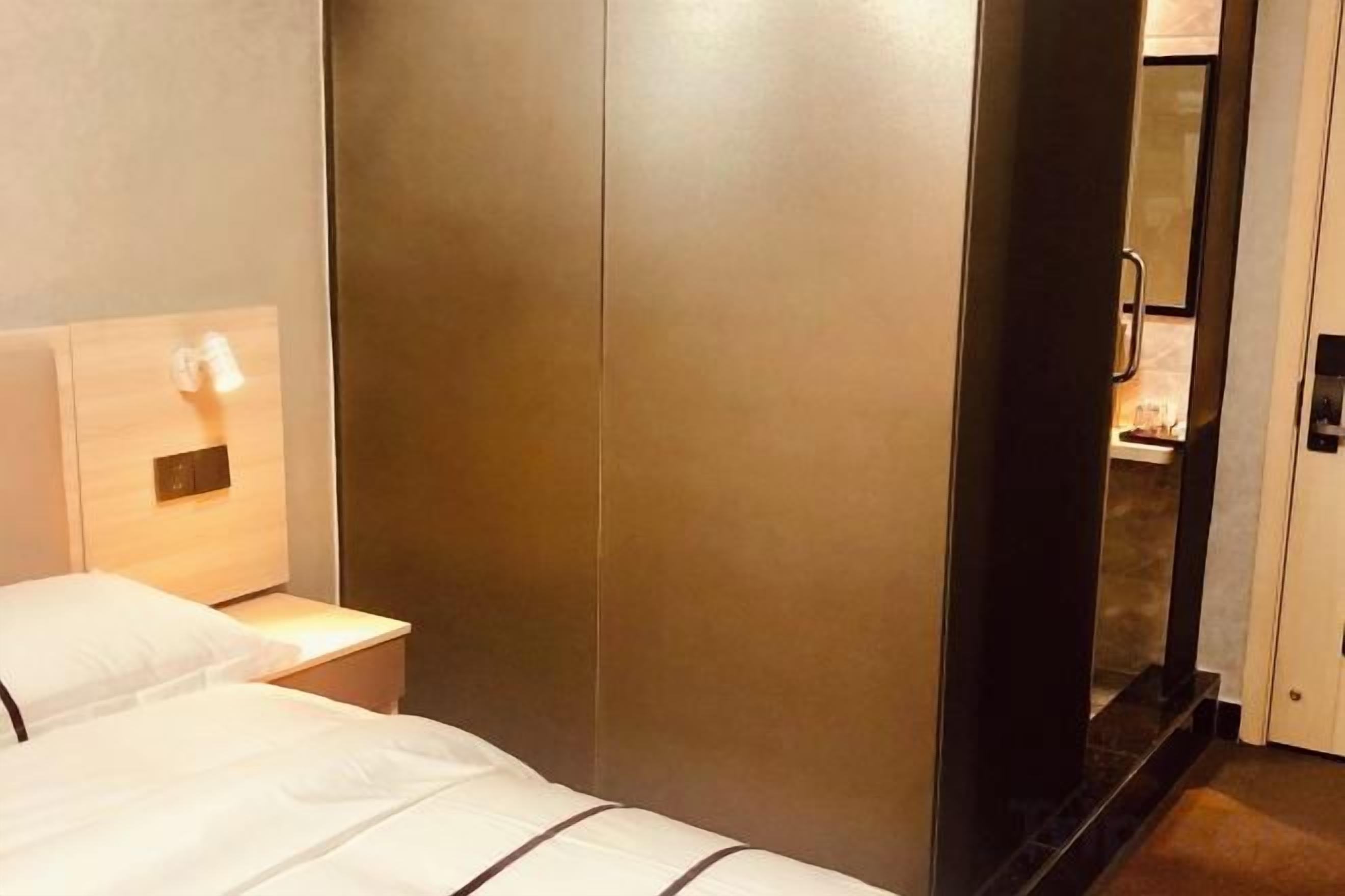 Una habitación de hotel con una cama, una mesita de noche y un armario.
