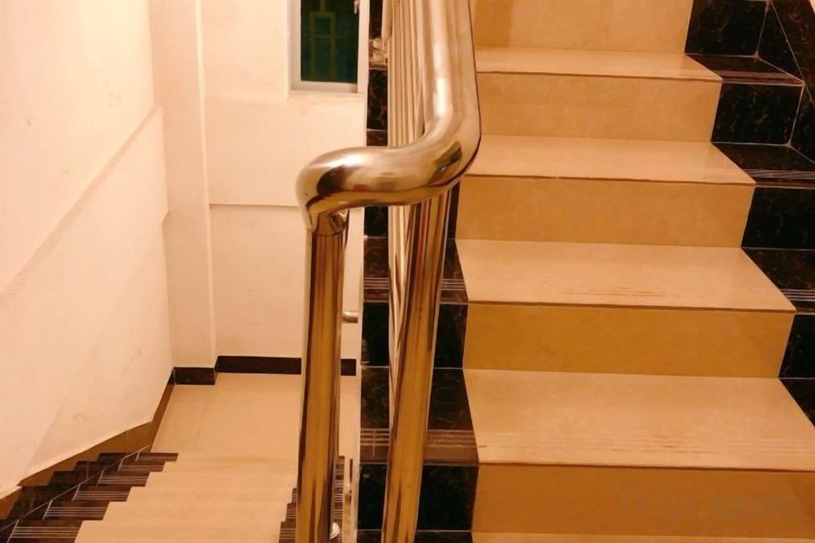 Un escalier doté d’une rampe métallique et de marches noires et beige.