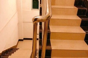 Una escalera con barandilla metálica y peldaños negros y beige.