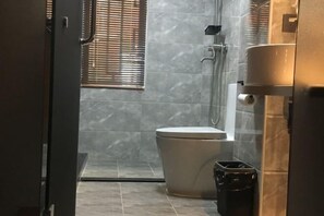 A bathroom with a toilet, a shower, and a trash bin. - Yuerong Boutique Hotel (Zhuhai)