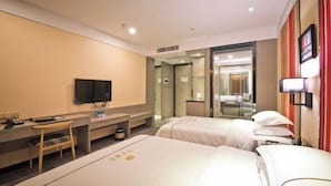 Quarto de hotel com duas camas, uma escrivaninha com cadeira, televisão e espelho.