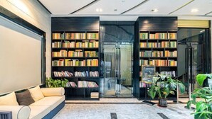 Uma biblioteca moderna com estantes, um sofá e plantas em vasos.