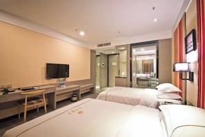 Quarto de hotel com duas camas, uma escrivaninha, uma cadeira, uma televisão e um espelho.