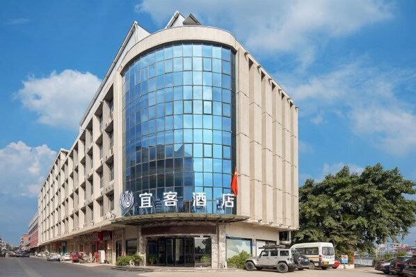 A hotel with a curved glass facade and a traditional building facade.