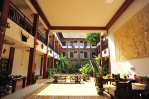 A spacious courtyard with a central seating area, surrounded by balconies and a large wall mural. - Jinghong Jinyun Inn (Gaozhuang Star Night Market) (Jinghong)