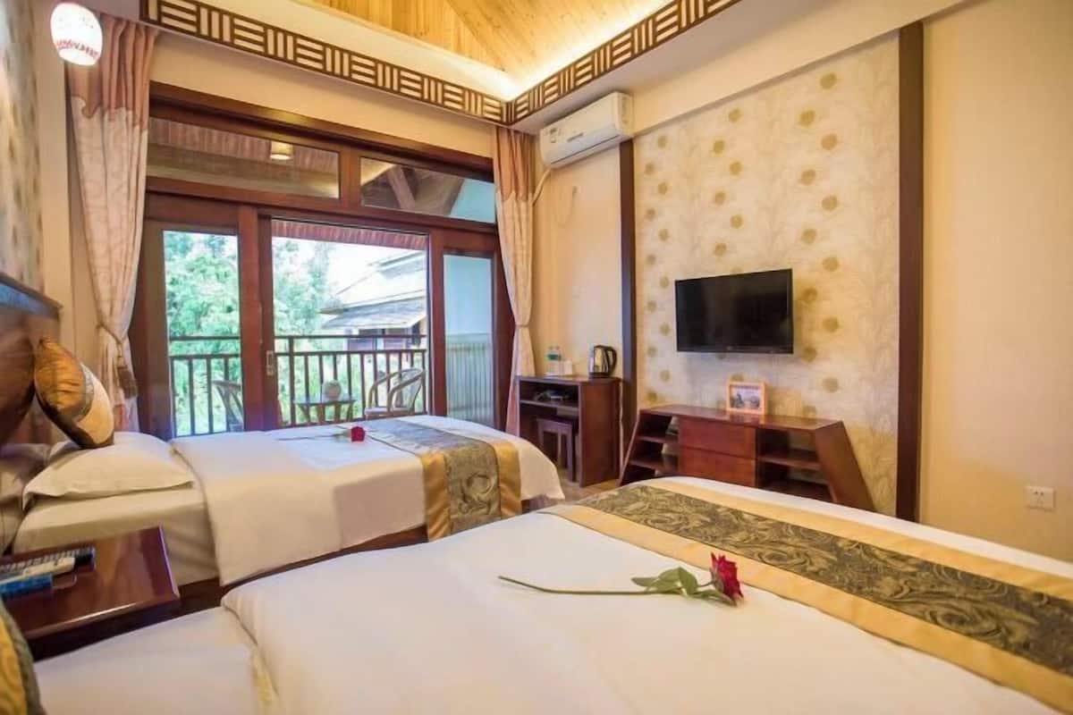 Une chambre d’hôtel avec deux lits, une télévision, un bureau et un balcon avec vue.