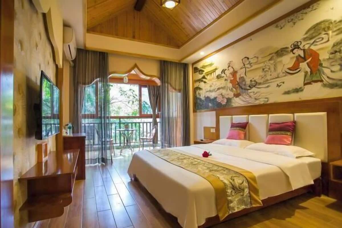 Une chambre d’hôtel avec un grand lit, un balcon offrant une belle vue et une fresque murale de style traditionnel.
