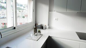 Una cocina moderna con un ventanal grande, encimeras blancas y un horno empotrado.