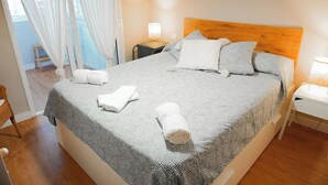 Una cama bien hecha con un edredón estampado, dos lámparas de noche y un cabecero de madera.