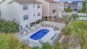 Ein Wohnhaus mit Schwimmbad, einer Terrasse mit Sitzgelegenheiten und einem eingezäunten Garten.