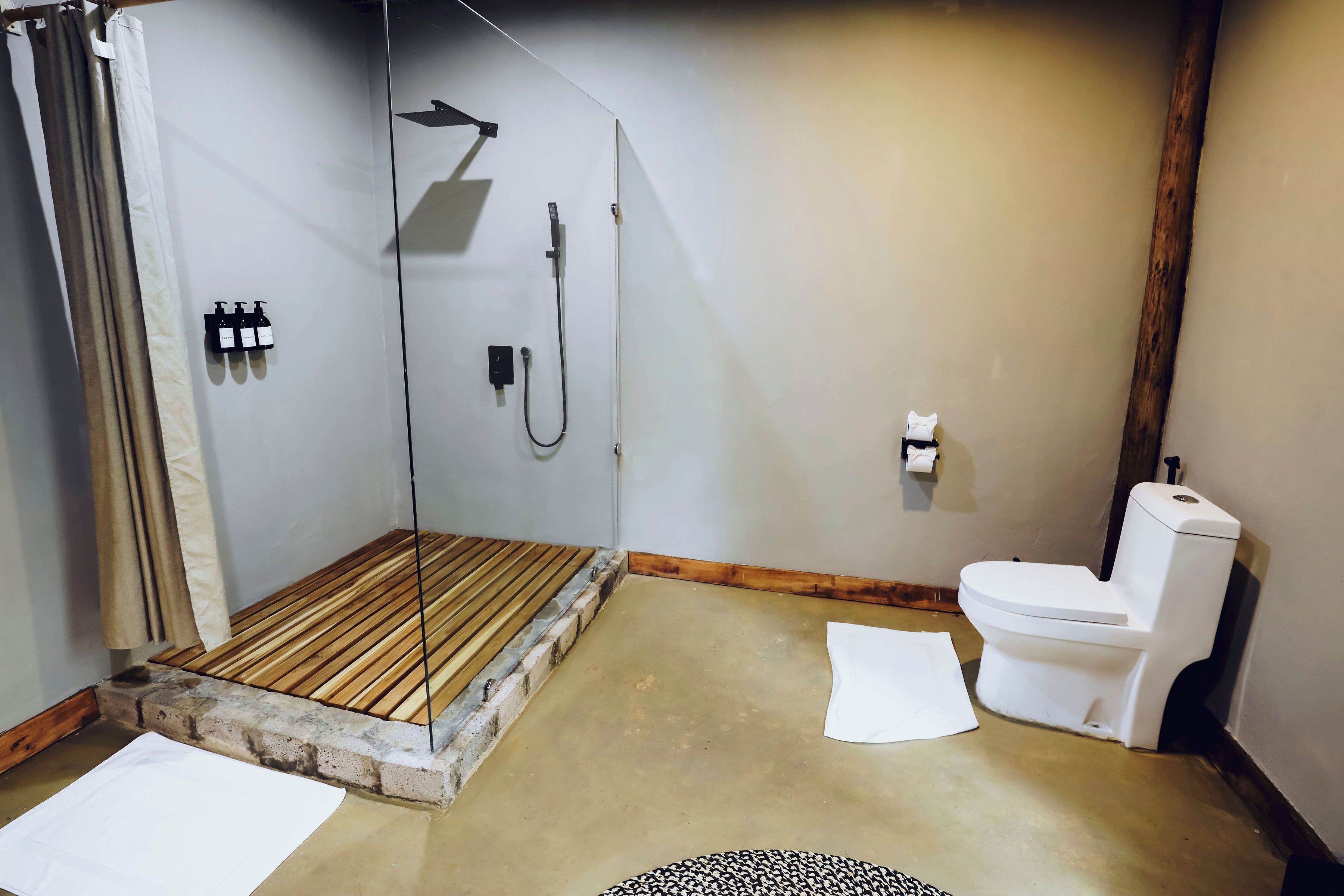 A bathroom with a shower, toilet, and a wooden bench.