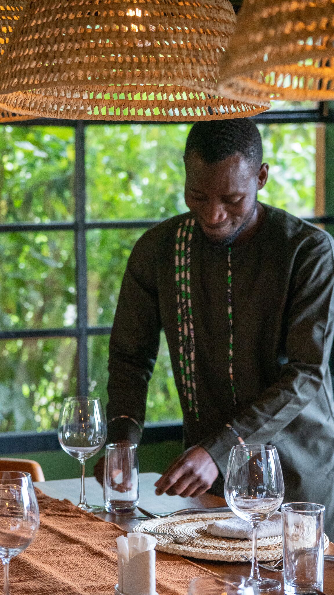 A person seated at a table with multiple wine glasses and a woven placemat.