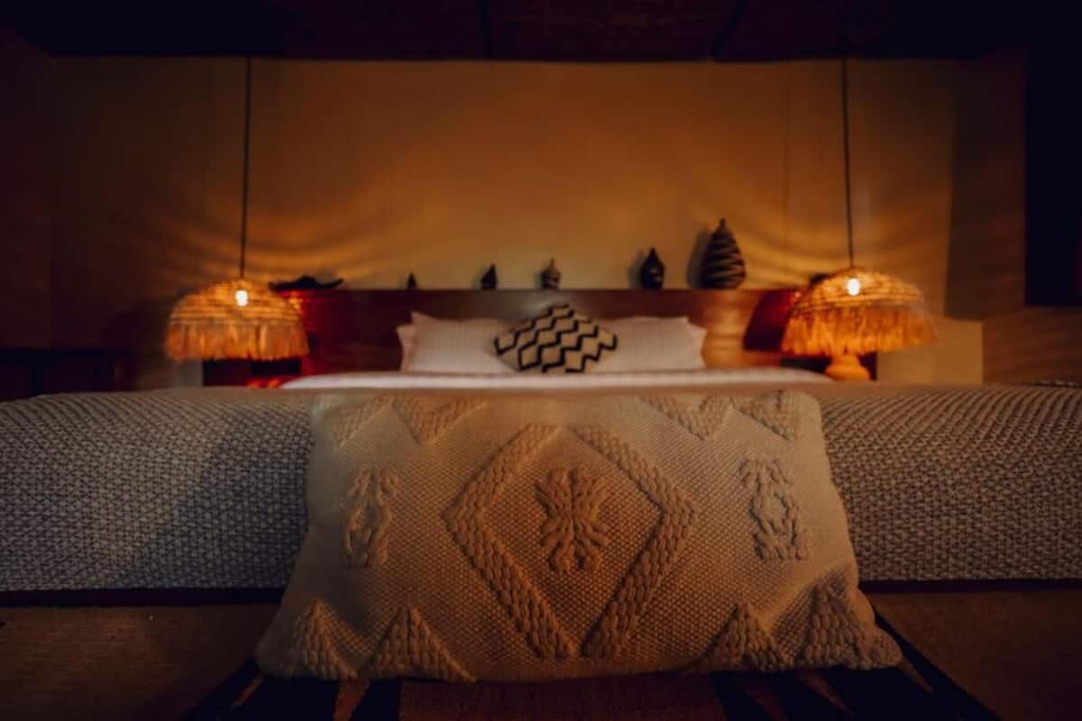A neatly arranged bedroom with a bed, two bedside lamps, and a decorative pillow.