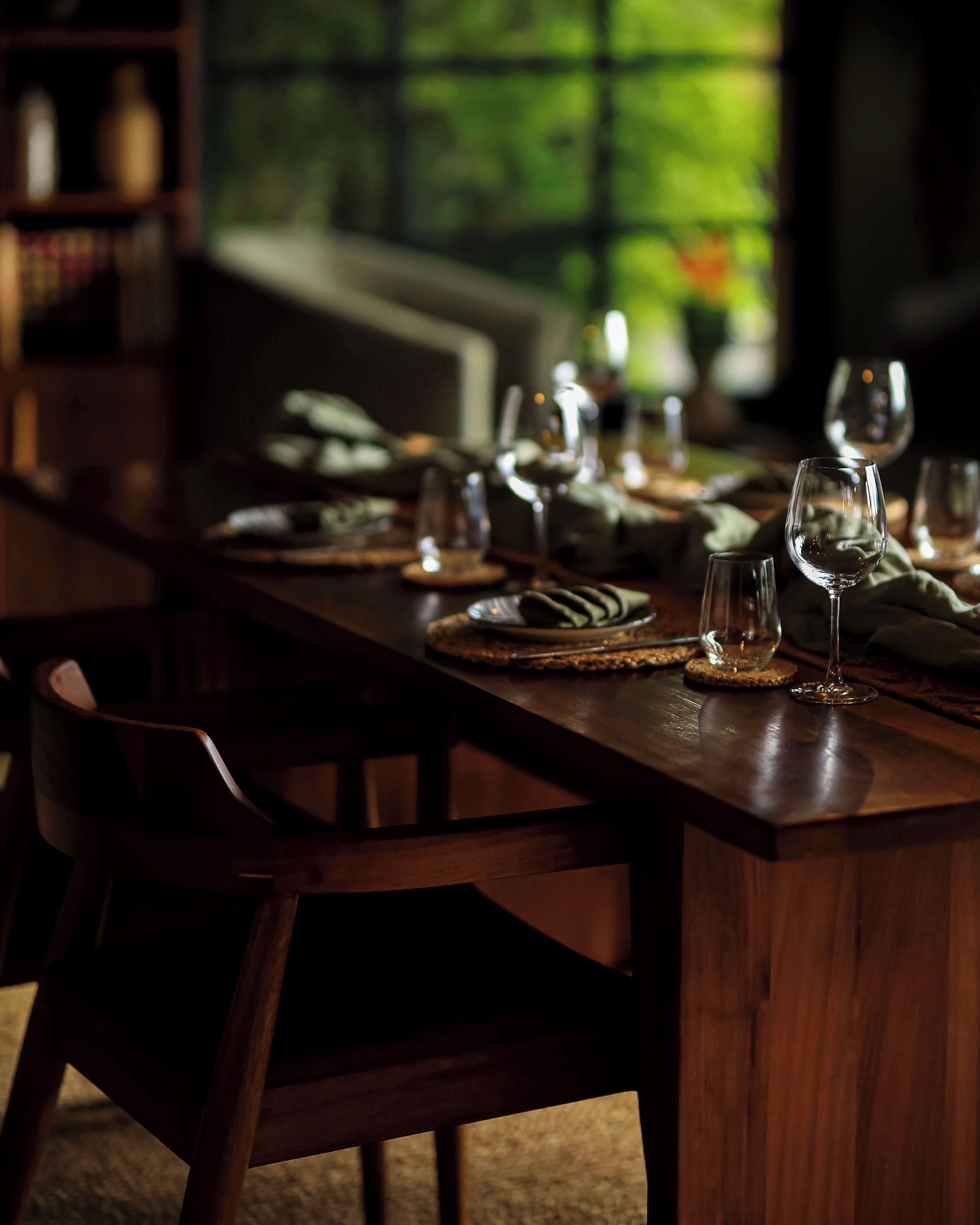 Una mesa de comedor dispuesta con platos, vasos y cubiertos, rodeada de sillas.