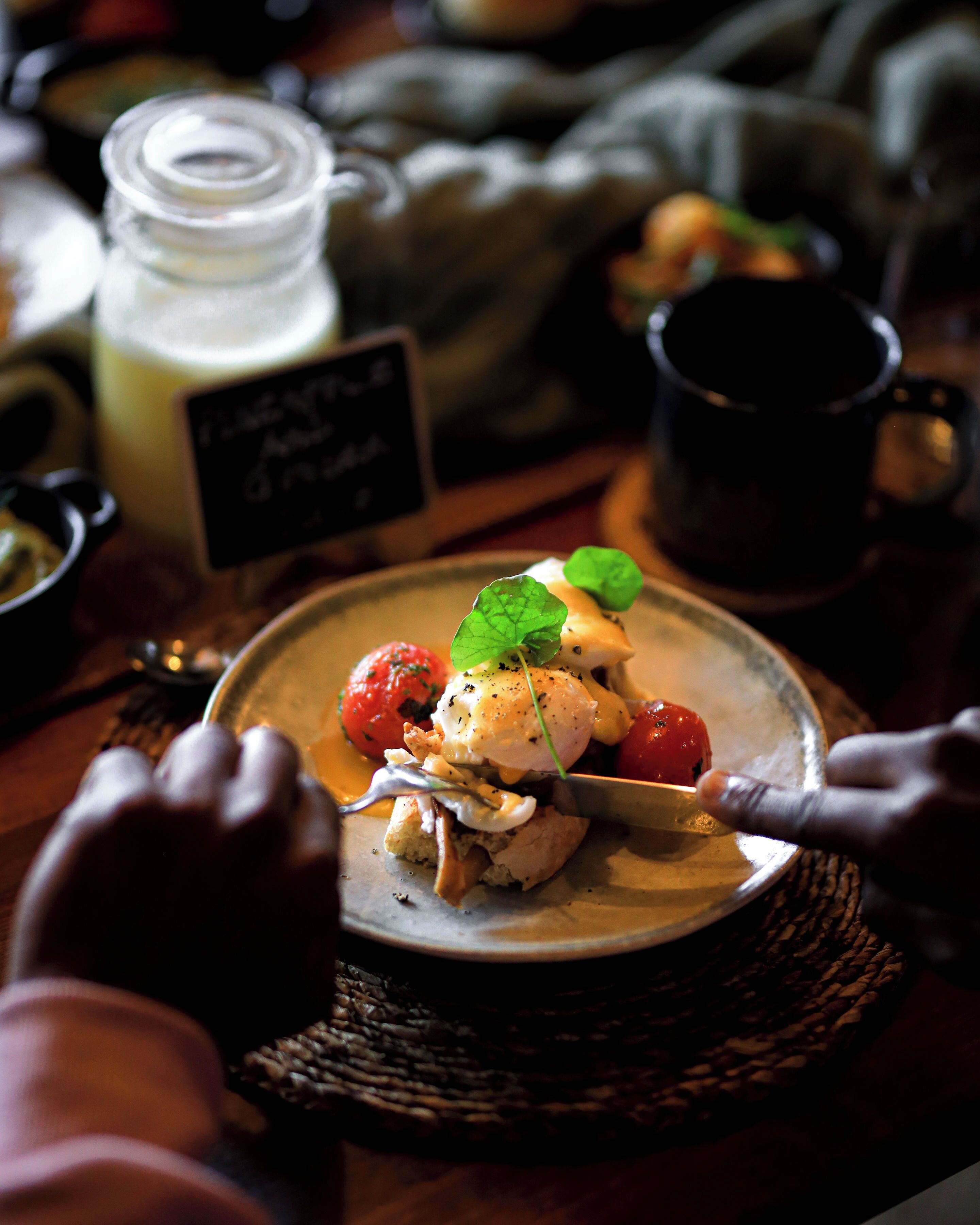 A dining table with a plate of food, a glass jar, and a black mug.