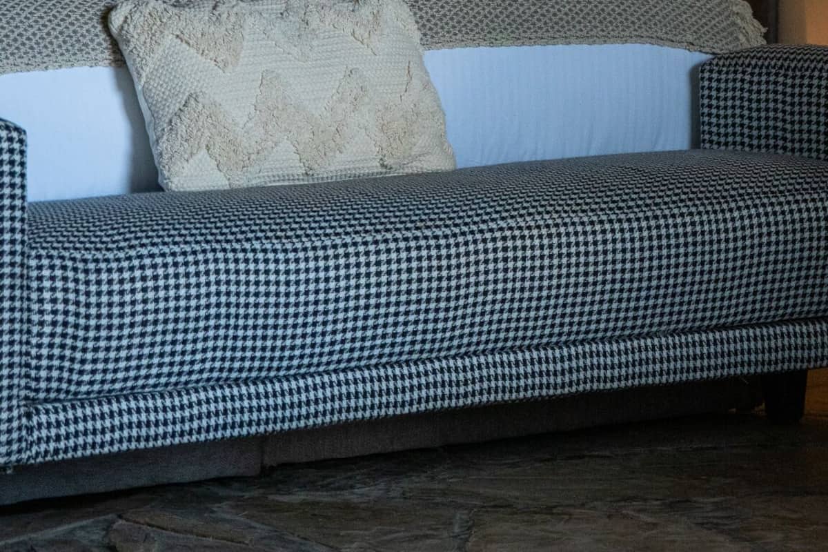 A bedroom with a bed, a patterned sofa, a hanging lamp, and a wall-mounted lamp.