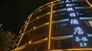 Un bâtiment dont l’enseigne, illuminée, est écrite en caractères chinois, ce qui indique qu’il s’agit d’un hôtel.