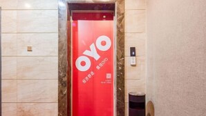 Un ascenseur à l’intérieur rouge, avec le logo « OYO » sur la porte.