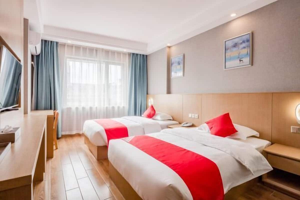 Quarto de hotel com duas camas, uma escrivaninha e uma televisão.
