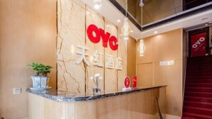 Un comptoir d’accueil avec un plateau en marbre, une plante en pot et un panneau arborant le logo « Oye ».