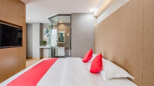 Une chambre d’hôtel moderne avec un grand lit, un téléviseur fixé au mur et une douche à parois de verre.