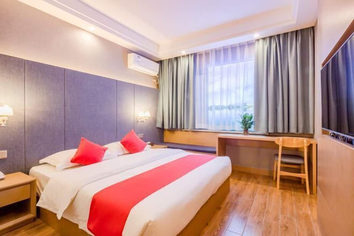Quarto de hotel com uma cama grande, uma escrivaninha e uma cadeira.