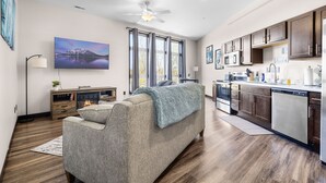 A modern living room with a sofa, a fireplace, and a large window. - Fantasy Field Condo #217 (DYERSVILLE)