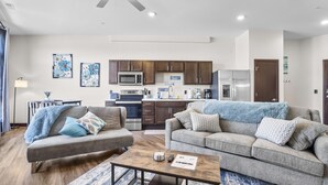 A modern living room with two sofas, a coffee table, and a kitchen area with dark cabinets and stainless steel appliances. - Fantasy Field Condo #217 (DYERSVILLE)