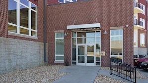A brick building with a stone facade, large glass doors, and a concrete pathway leading to the entrance. - Fantasy Field Condo #217 (DYERSVILLE)