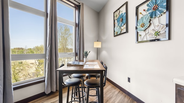 A dining area with a table, four stools, a lamp, and two framed floral artworks on the wall. - Fantasy Field Condo #217 (DYERSVILLE)