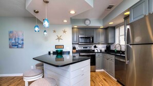 A modern kitchen with grey cabinets, stainless steel appliances, and a central island with stools. - < 1 Mi to Ocean: North Myrtle Beach Condo (North Myrtle Beach)