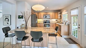 Una cocina moderna con una isla central, electrodomésticos de acero inoxidable y una lámpara colgante.