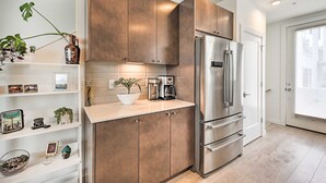 Una cocina moderna con electrodomésticos de acero inoxidable, armarios de madera y encimera blanca.