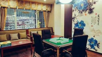 A room with a sofa, a table with a board game, and a wall with floral artwork.
