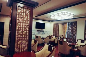 Habitación de hotel con zona de comedor, televisor montado en la pared y un biombo decorativo.