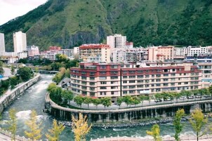 Un hotel de varios pisos con un río al frente, rodeado de vegetación y colinas.