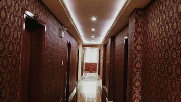 A long, narrow hallway with patterned walls and doors, leading to a room with a red accent wall.