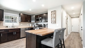 A modern kitchen with dark wood cabinets, a central island, and a built-in microwave. - High Point Guesthouse (Seattle)