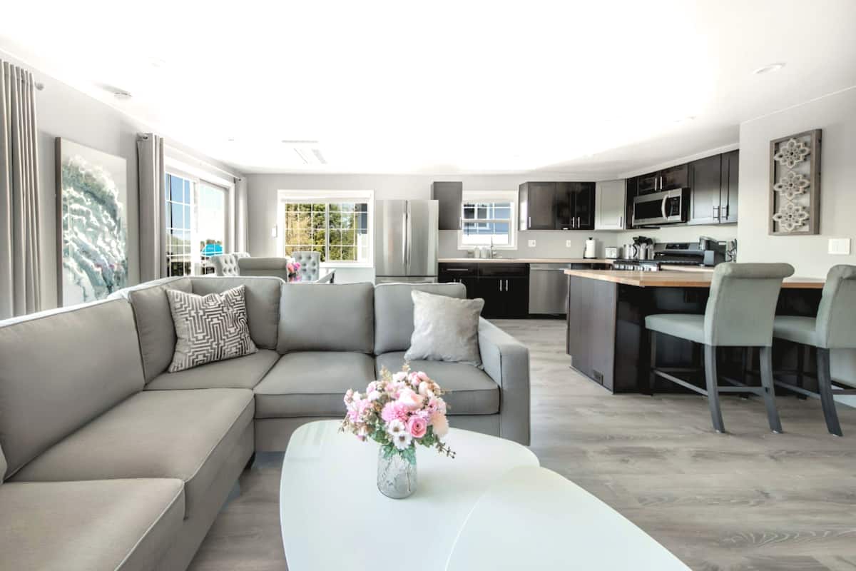 A modern living room with a grey sectional sofa, a white coffee table, and a vase of flowers.