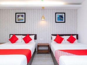 A hotel room with two beds, each with white bedding and red pillows. There are two framed pictures on the wall, a small wooden nightstand between the beds, and a ceiling light fixture. - Big Big Hotel (Johor Bahru)