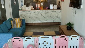 A hotel reception area with a reception desk, a sofa, a play area with toys, and a TV mounted on the wall. - Big Big Hotel (Johor Bahru)