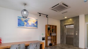 A dining area with a wooden table and two chairs, a bookshelf, a map on the wall, and an elevator. - Big Big Hotel (Johor Bahru)