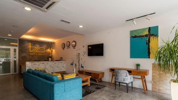 A modern living room with a blue sofa, a wooden desk, and a television. - Big Big Hotel (Johor Bahru)