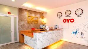 A hotel reception desk with a marble counter, a wooden bench, and a wall with clocks showing different cities. - Big Big Hotel (Johor Bahru)